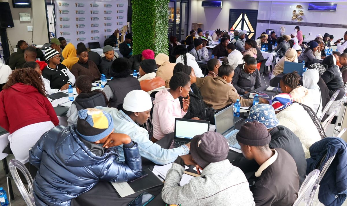 A full room of NIBS learners working on laptops at long tables during a cohort session.