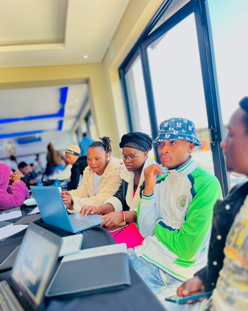 Learners concentrating on a laptop screen together at a NIBS session.